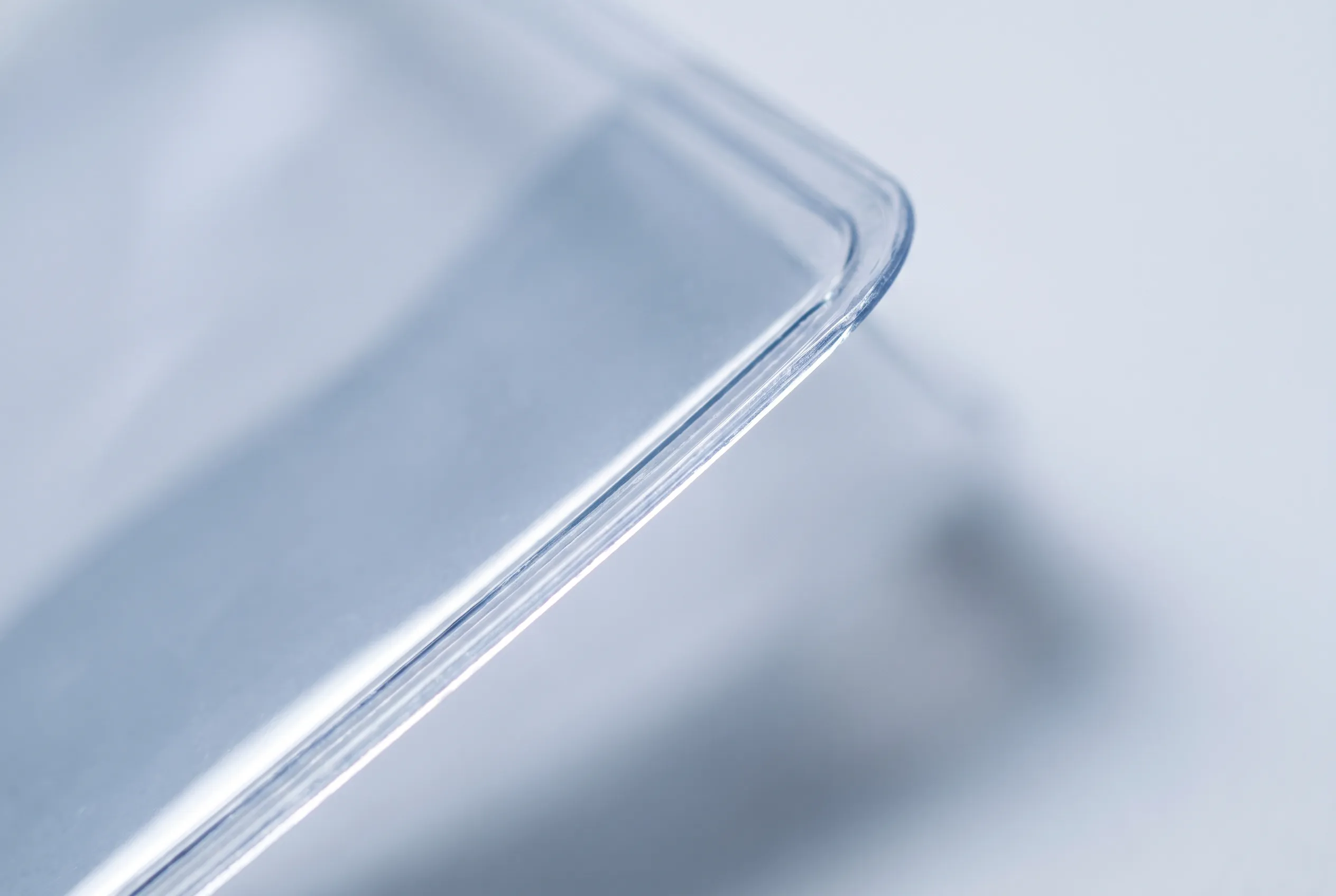 Macro view of the cleanly cut edge of a clear PVC pouch, with light transmitting along the edge.